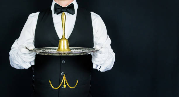 istock Butler Holding Gold Bell on Silver Serving Tray 1980309874