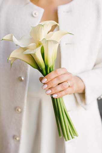 Delicate white bouquet of calla lilies in the hands of the bride at the wedding
