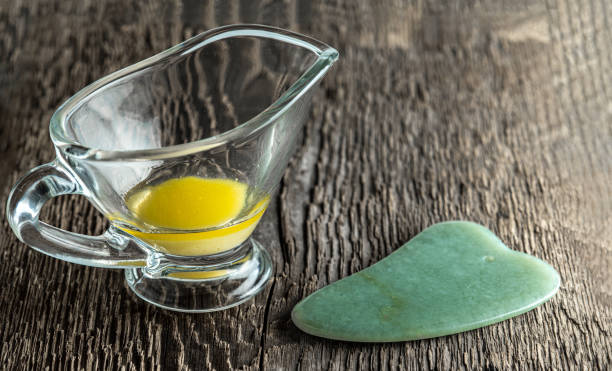 istock Jade scraper for gua cha and melted ghee in a glass cup on 1980318950