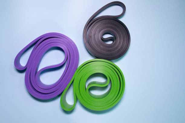 istock Multicolored exercise rubber band fitness on blue background. 1980345969