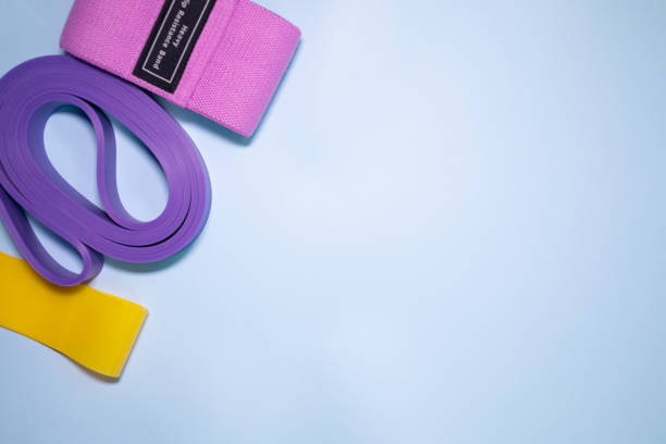 istock Multicolored exercise rubber band fitness on blue background. 1980347535