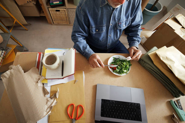 istock Senior man eating salad while working at home 1980350671