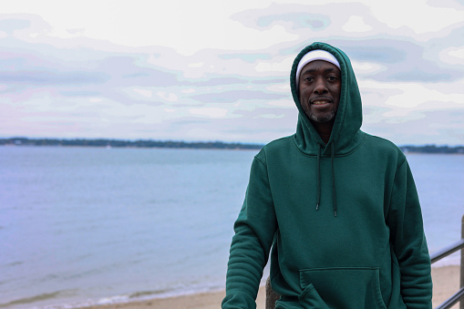 A portrait of a black man smiling by the ocean