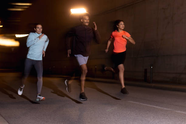 istock Group Resilience Run: Three young athletes Pushing Hard, Building Bonds Through Shared Effort outdoors at night 1980381030
