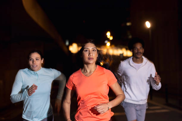istock Night Run Concentration: Group of Three athletes Demonstrates Collective Focus 1980382063