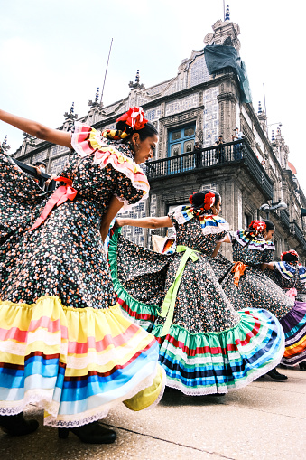 A group of women dancing traditional Mexico folk dance in colorful dress perform in Mexico City, Mexico