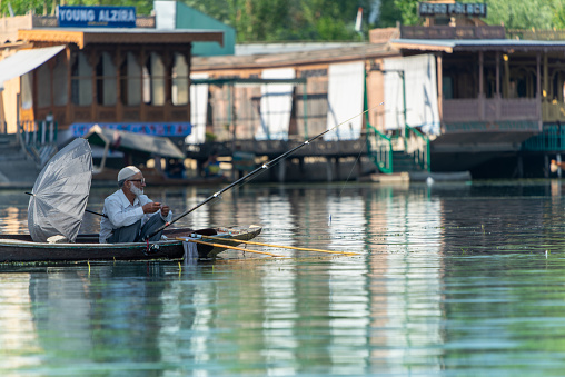 Srinagar, India 07 - June 2018: Dal Lake lifestyle. A local man is fishing on a boat. This is the local transportation in the lake of Srinagar. Jammu and Kashmir state, India.