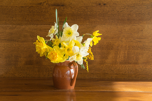 A beautiful large bouquet of multi-colored daffodils in a white basket on a transparent table. Gift for mom on March 8th.