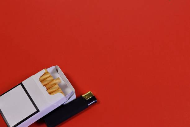 istock An open pack of cigarettes and a black lighter on a red background. 1980471299