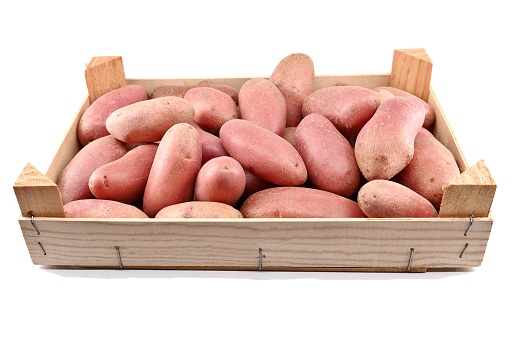 Crate full of raw red potatoes on white background.