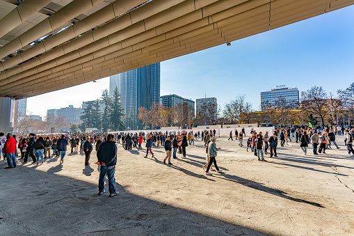Madrid, Spain. Panoramic view of hundreds of fans moving around the Santiago Bernabeu stadium against a backdrop of business buildings. Football afternoon