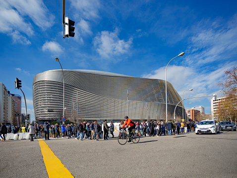 Madrid, Spain. Fans, cyclists, and vehicles circulating around the vicinity of the Santiago Bernabeu stadium on match day.