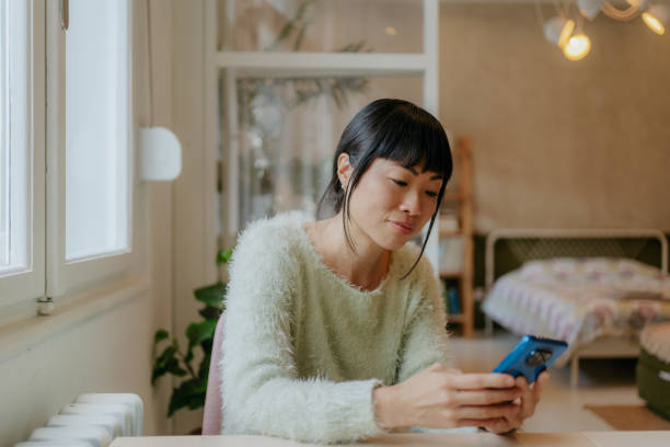 istock Beautiful Japanese woman using a smartphone at home 1980526575