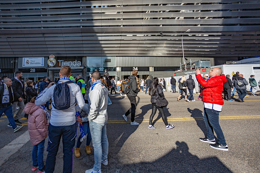 Madrid, Spain. Real Madrid fans move around, take photos, and take selfies in the surroundings of the Santiago Bernabeu stadium before the match.