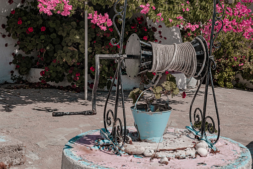 old type water well with pot flowers, blue vintage colors, colorful blooming begonville flowers