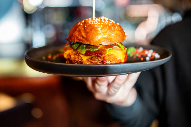 istock waiter holding plate with burger at cafe 1980572168