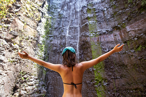 Young girl exploring waterfall in Madeira island