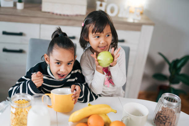 istock Two smiling little girls having healthy breakfast 1980620141