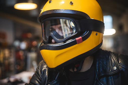 Close up of man wearing helmet on motorcycle indoor in motor shop