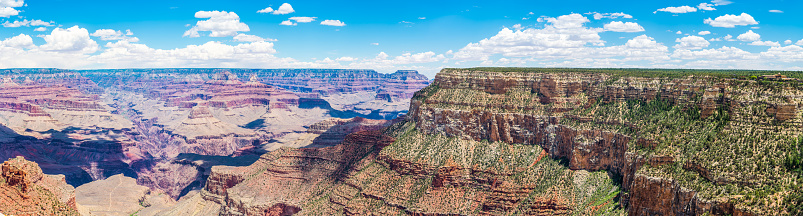 Panoramic view from the South Rim below little fluffy clouds over the iconic strata, mesas and ravines of the Grand Canyon National Park, Arizona, USA.