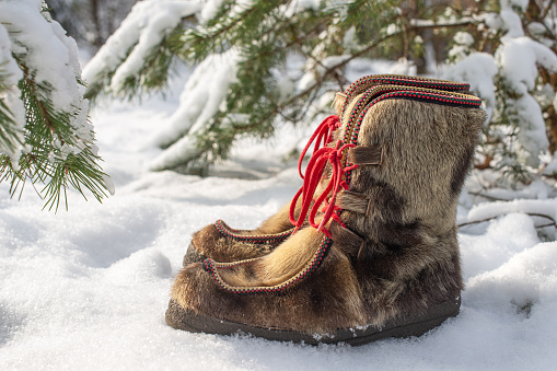Scandinavian winter footwear made of leather with reindeer fur and red shoelaces.