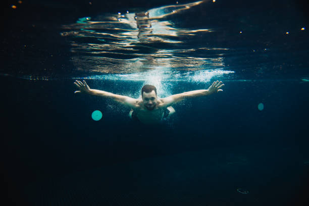 istock A young man swims underwater in a pool. Summer vacation concept. 1980735395