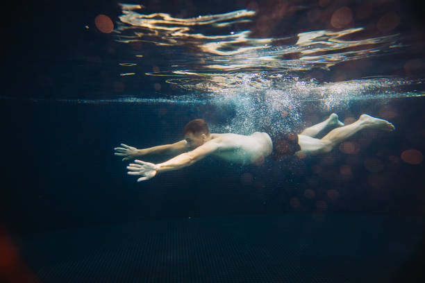 istock A young man swims underwater in a pool. Summer vacation concept. 1980735915