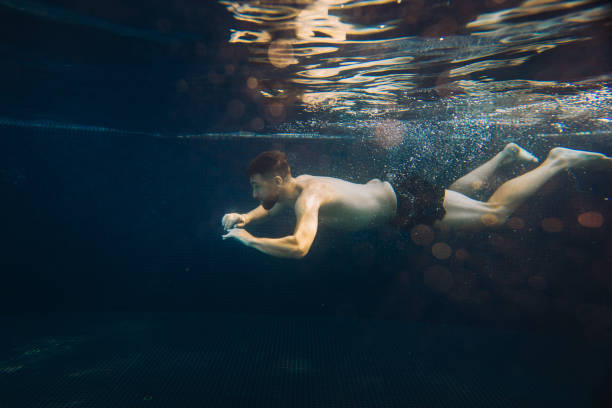 istock A young man swims underwater in a pool. Summer vacation concept. 1980736430