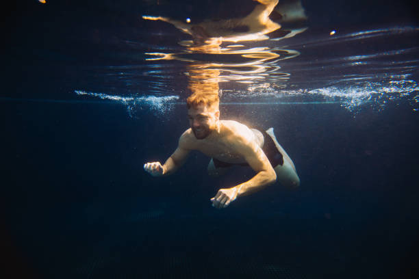 istock A young man swims underwater in a pool. Summer vacation concept. 1980736438
