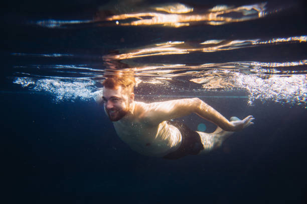 istock A handsome young man swims underwater in a swimming pool while on vacation. 1980736951