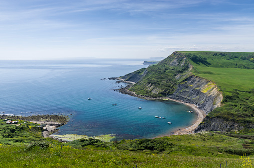 View of Chapman's Pool and cliffs of the Jurassic Coast World Heritage site in Dorset, England. Looking west towards Weymouth. On the left in the extreme distance is the Isle of Portland next to Weymouth harbour. Very warm summer day in June.