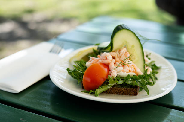 Open sandwich with fresh shrimps, lettuce, cucumber, tomato, mayonnaise and lemon on a slice of bread. Photo taken in Sweden.