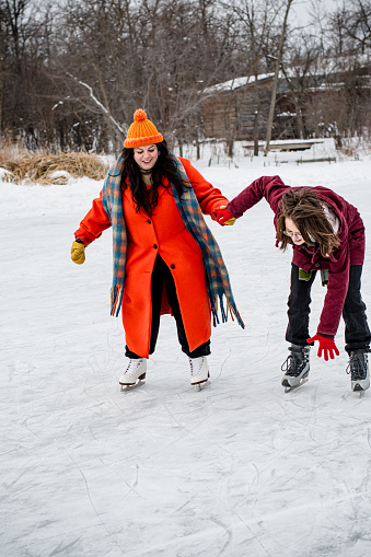 In a heartwarming scene of support, the gender fluid individual  extends a helping hand to a trans teen finding balance on the ice. a collective winter journey filled with warmth and encouragement with their found family