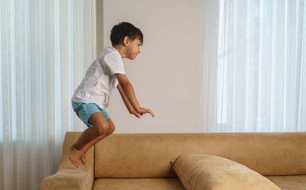 istock Cute little boy jumping and playing in a sofa at home 1980780193