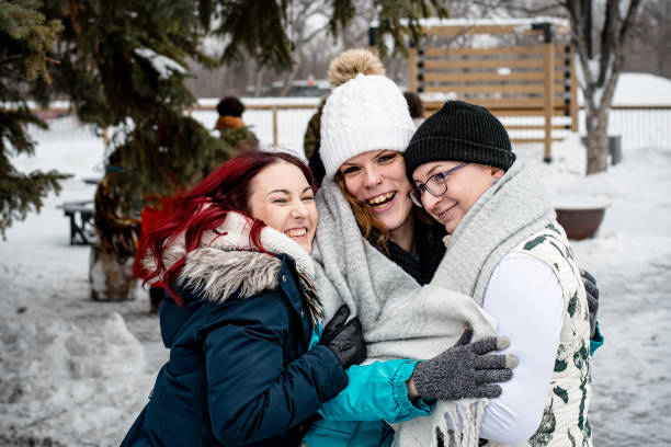 istock Winter Trio Embrace: Trans Women and Supportive Friend's Joyful Jump 1980802404