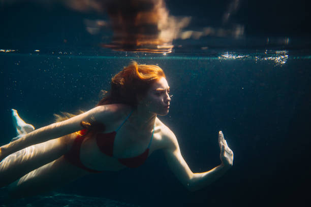 istock Young redheaded woman swimming underwater in a pool 1980816549