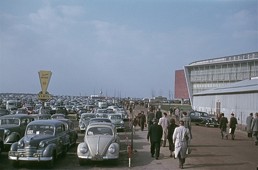 Near Hanover, Lower Saxony, Germany, 1955. The parking lot in front of the Hanover Trade Fair. Furthermore: trade fair visitors and cars.