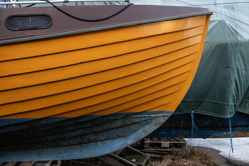 Yellow wooden boat laid up on land.