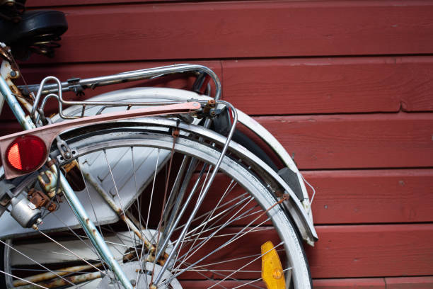 Two bikes parked by a red wooden wall.
