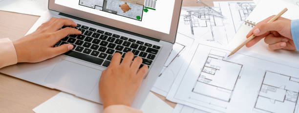 istock Eco house blueprint displayed on a laptop. Focus on hand. Closeup. Delineation. 1980872622