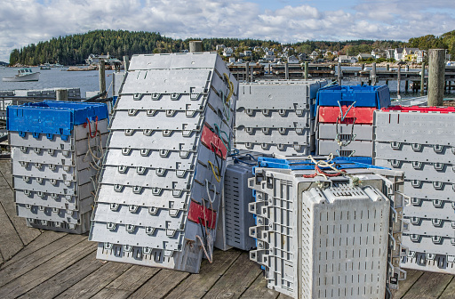 Plastic crates for storing and shipping fresh lobsters sit in stacks on a New England dock.