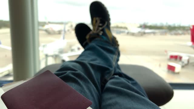 POV Point of view shot of a young male holding his passport and airline ticket, waiting in the departure area for taking his airplane at Miami International Airport.