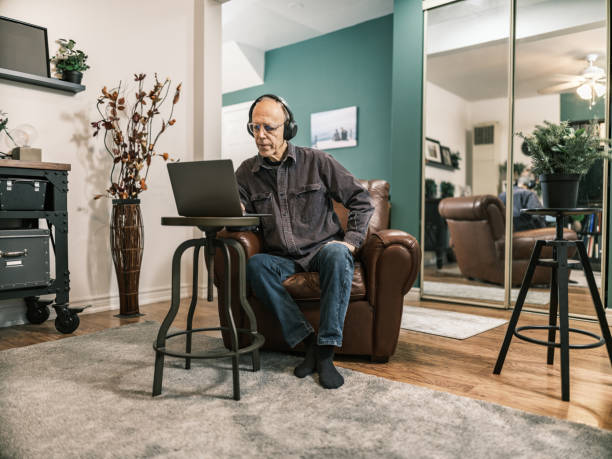 istock Senior man using laptop in his living room 1980971156