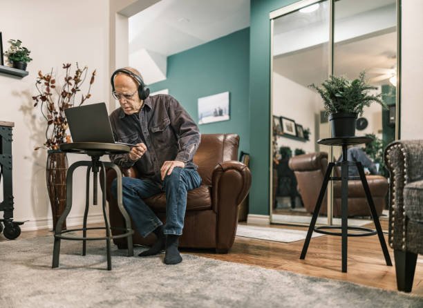 istock Senior man using laptop in his living room 1980971170