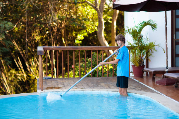 istock Boy cleaning swimming pool. Maintenance, service. 1980983103