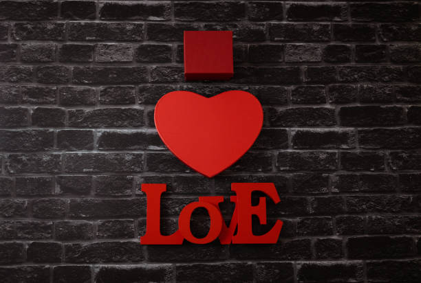 Two gift box in the shape of a red heart and a tree word love lies in the center on a black brick background, flat lay closeup. The concept of Valentine's Day, love day.