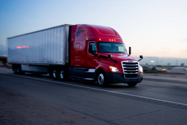 istock Red Semi-Truck Speeding Down Highway at Dusk 1981118295