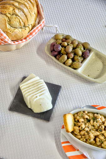 Delicious array of Portuguese starters: fresh bread, mild cheese, tempting olives, and tuna with black-eyed peas, perfect for any restaurant.