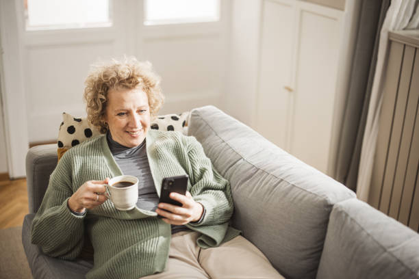 istock Relaxed smiling woman sitting on sofa using phone 1981189329