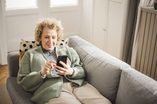 istock Relaxed smiling woman sitting on sofa using phone 1981189330